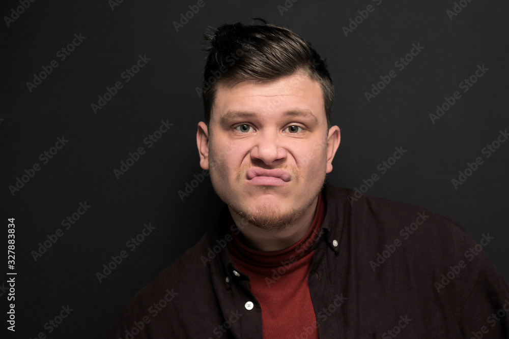 Portrait of young grimacing man isolated on gray background Portrait of young grimacing man isolated on gray background