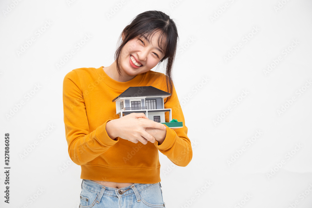 Young Asian woman smiling and hugging dream house sample model isolated over white background, Real estate and home insurance concept Young Asian woman smiling and hugging dream house sample model isolated over white background, Real estate and home insurance concept