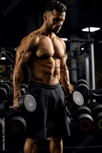 Shirtless male bodybuilder holding dumbbells.