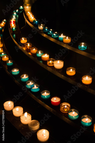 Group of colorful glowing candles in the dark. Ancient christian tradition.