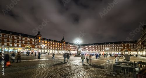 People in Plaza Mayor under a cloudy sky at night