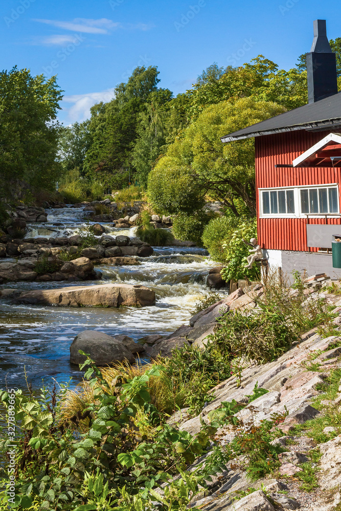 The picturesque view of Vanhakaupunki, the oldest part of Helsinki. The Vantaa river landscape. Red wooden house.