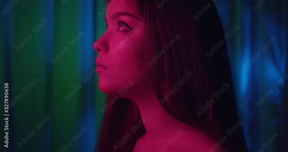 Close-up girl portrait pink light neon fashion joy view profile flirt blue background modest