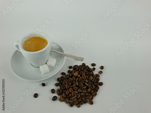 Eine Kaffetasse mit Untertasse neben Kaffebohnen