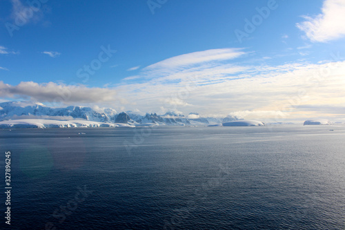 Soft sunset lights on snow-capped mountains and icy shores in the Antarctic Peninsula, Antarctica