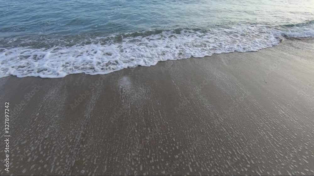 Sandy beach with moving and foaming waves at sunrise Sandy beach with moving and foaming waves at sunrise