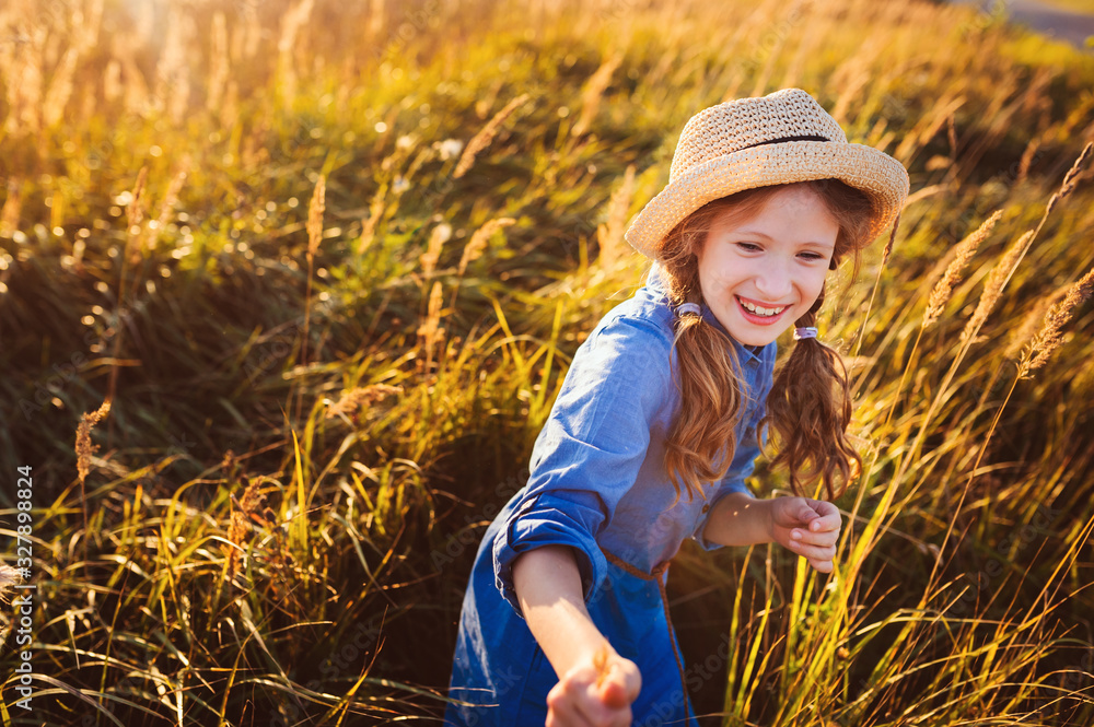 happy kid girl in blue dress and straw walking on summer sunny meadow. Lifestyle shot, rural living and summer traveling concept happy kid girl in blue dress and straw walking on summer sunny meadow. Lifestyle shot, rural living and summer traveling concept