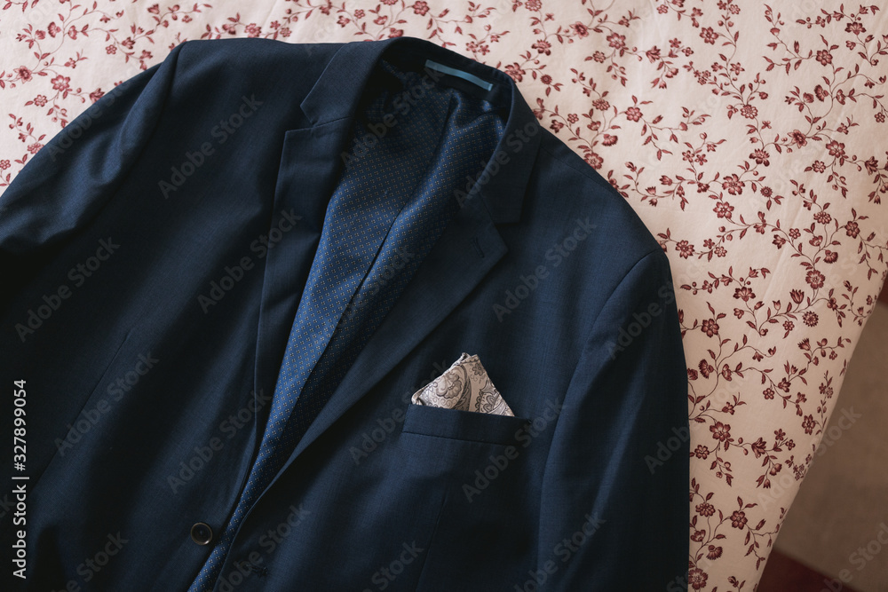 Close up photography of an isolated jacket suit resting in a bed with flowers pattern. Essential clothes for a wedding ready to wear. Close up photography of an isolated jacket suit resting in a bed with flowers pattern. Essential clothes for a wedding ready to wear.
