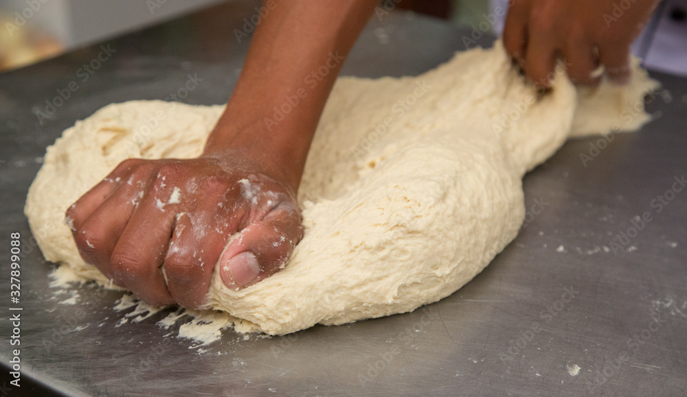 Hands knead dough on a metal surface Hands knead dough on a metal surface