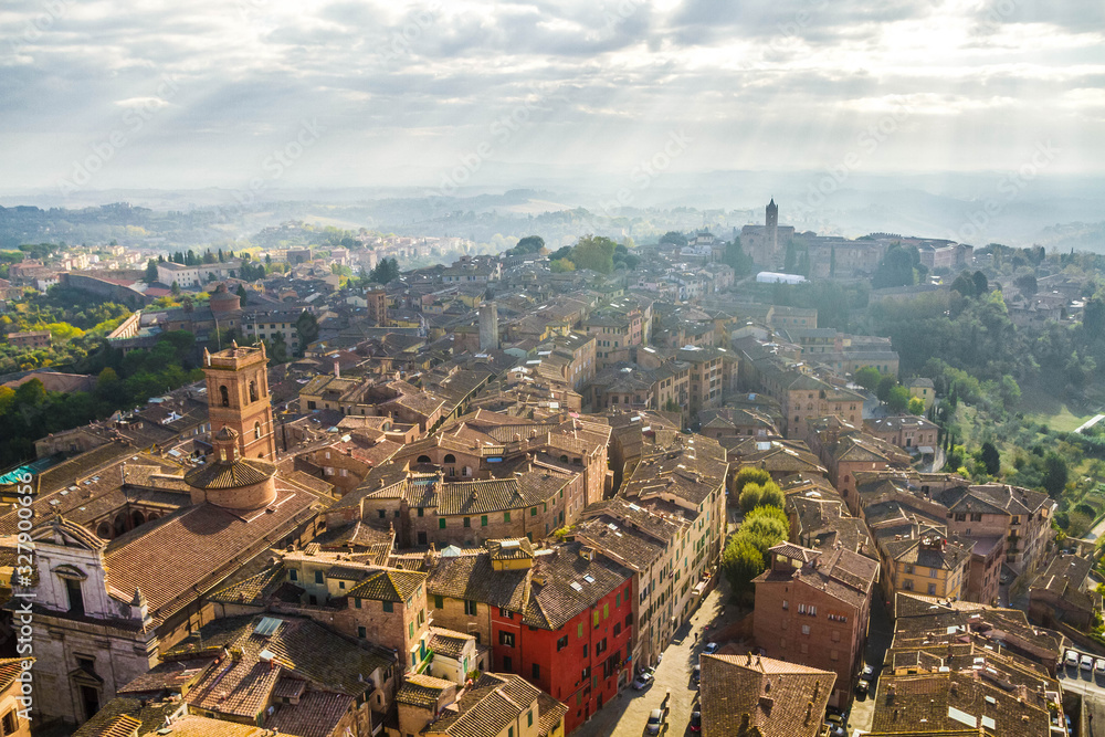 Panoramic view of Siena from The Torre del Mangia. Medieval houses are located on the hillsides, tuscan hills on the horizon, church of San Martino. Pictorial cityscape. Tuscany, Italy.