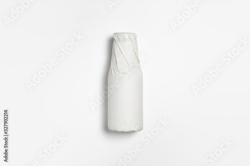 Bottle wrapped in white paper on white background.Mockup.High resolution photo.