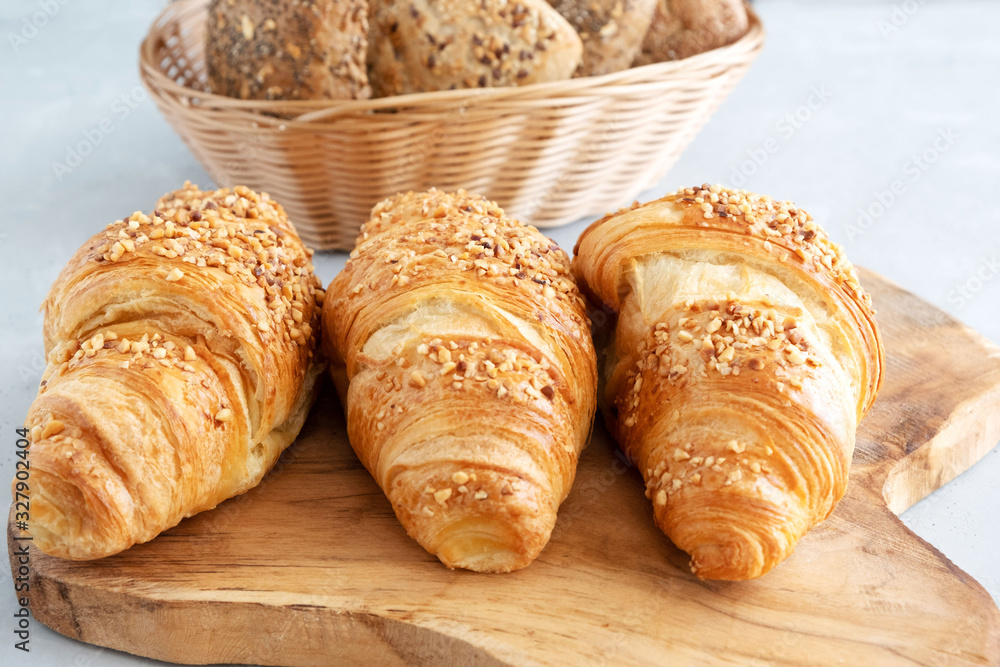 Three fresh traditional french croissants on a wooden board. Close-up. Morning croissants with nuts. Traditional french baking