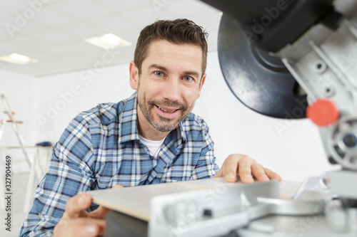 handsome man carpenter using a circular saw