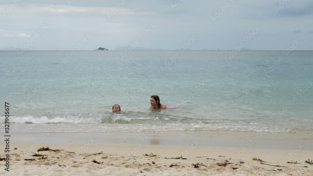 Mother and daughter swim in sea water. Cheerful happy family vacation at resort Mother and daughter swim in sea water. Cheerful happy family vacation at resort
