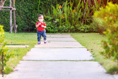 Cute baby boy walking at the park walking with wearing a dust mask protect for PM2.5 and as protection new virus COVID-19.