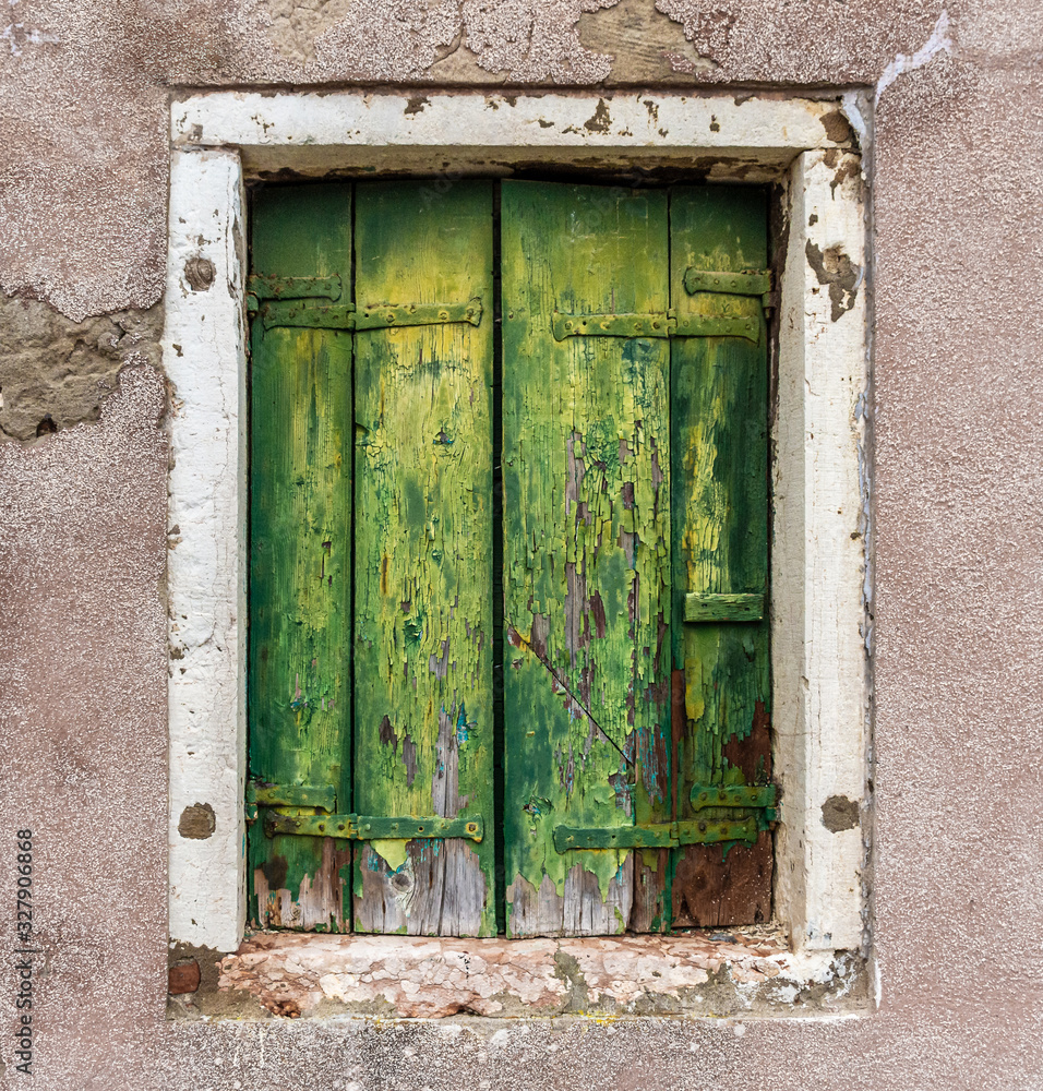 Old green weathered shutters with a white window frame