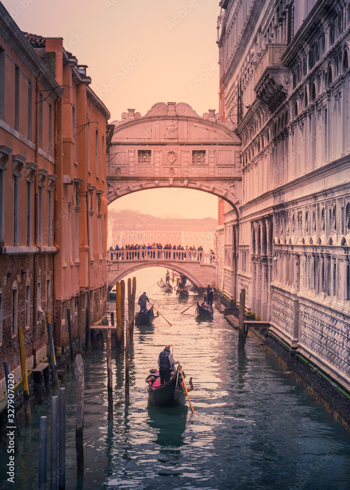 Gondoliers row under the Bridge of Sighs on an atmospheric winter day in Venice