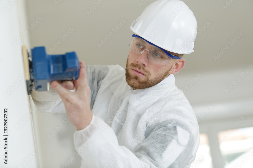 a young builder sanding wall a young builder sanding wall