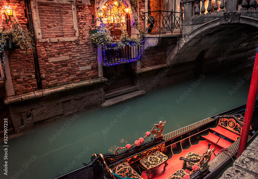 moored gondola on narrow canal with bridge and christmas lights