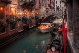 water taxi passes under a bridge on a narrow venice canal