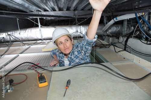 female electrician pulling cables in the ceiling