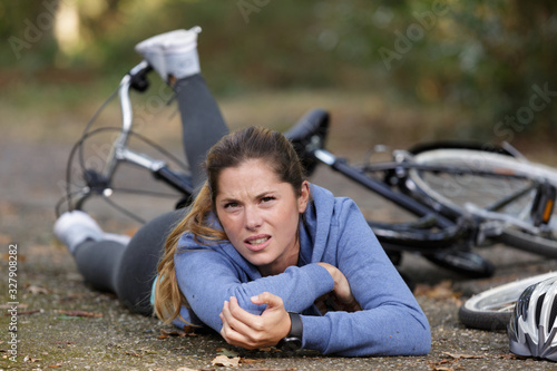 young woman fallen from bicycle and holding her elbow