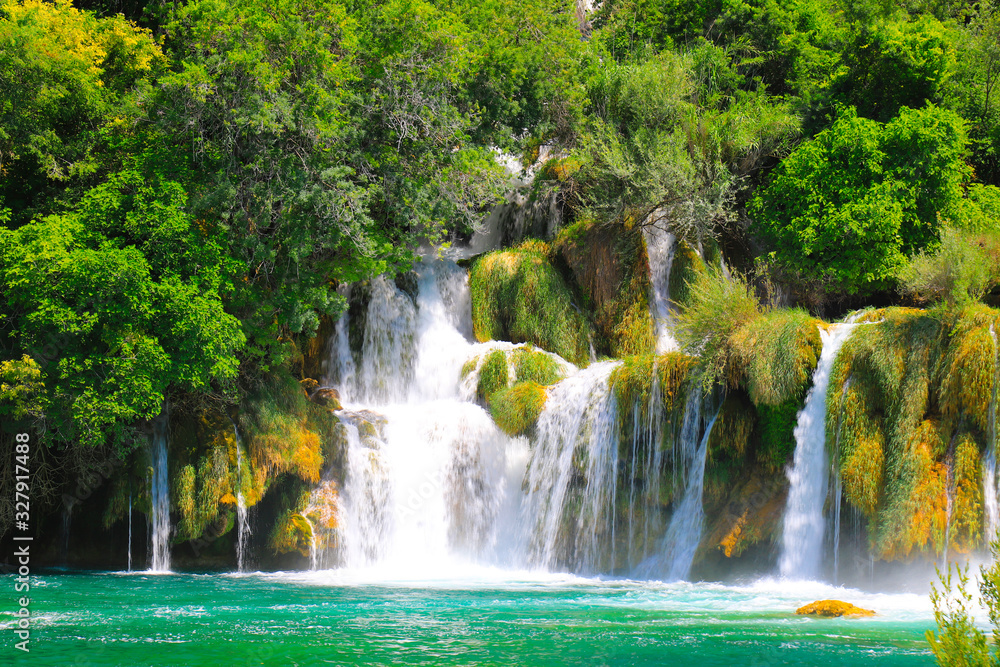 A picturesque cascade waterfall among large stones in the Krka National Landscape Park, Croatia in spring or summer. The beautiful Croatian waterfalls, mountains and nature.