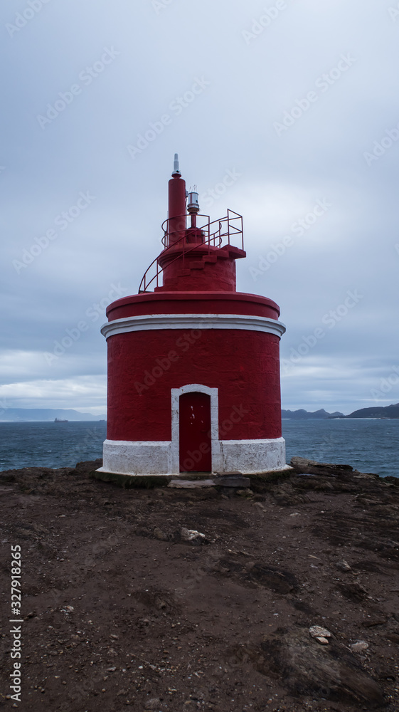Red Lighthouse in front of the Sea on a cloudy day