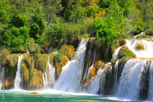 A picturesque cascade waterfall among large stones in the Krka Landscape Park  Croatia in spring or summer. The big beautiful Croatian waterfalls  mountains and nature.