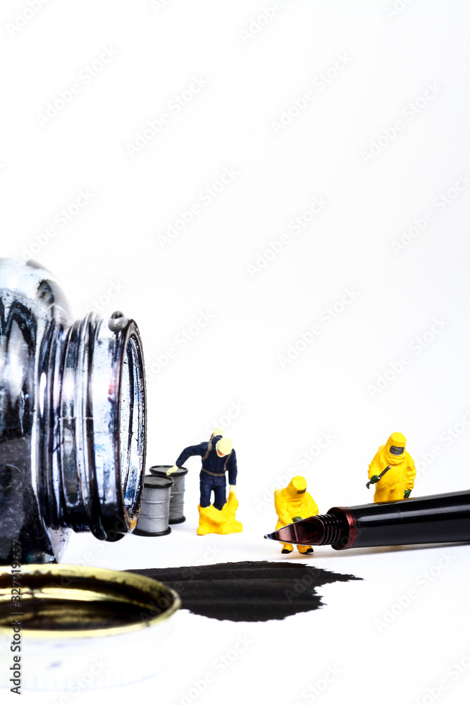 Conceptual image of miniature figure people wearing hazmat suits inspecting a fountain pen and spilled ink with copy space