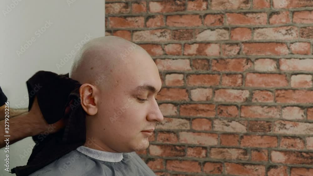 Close up view of barber wiping head of client with towel. Professional stylist working with client. Male beauty concept Close up view of barber wiping head of client with towel. Professional stylist working with client. Male beauty concept