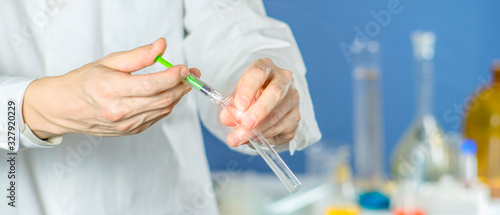 scientist dropping chemical liquid to flask with lab glassware background, Laboratory research concept,Researcher is dropping the reagent into test tube. © Michael