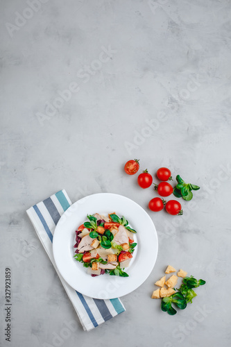 Fresh Caesar salad with delicious chicken breast, spinach, cabbage, arugula, Parmesan and cherry tomatoes on a light background. Caesar sauce, lemon, broken cheese. The concept of healthy and dietary 