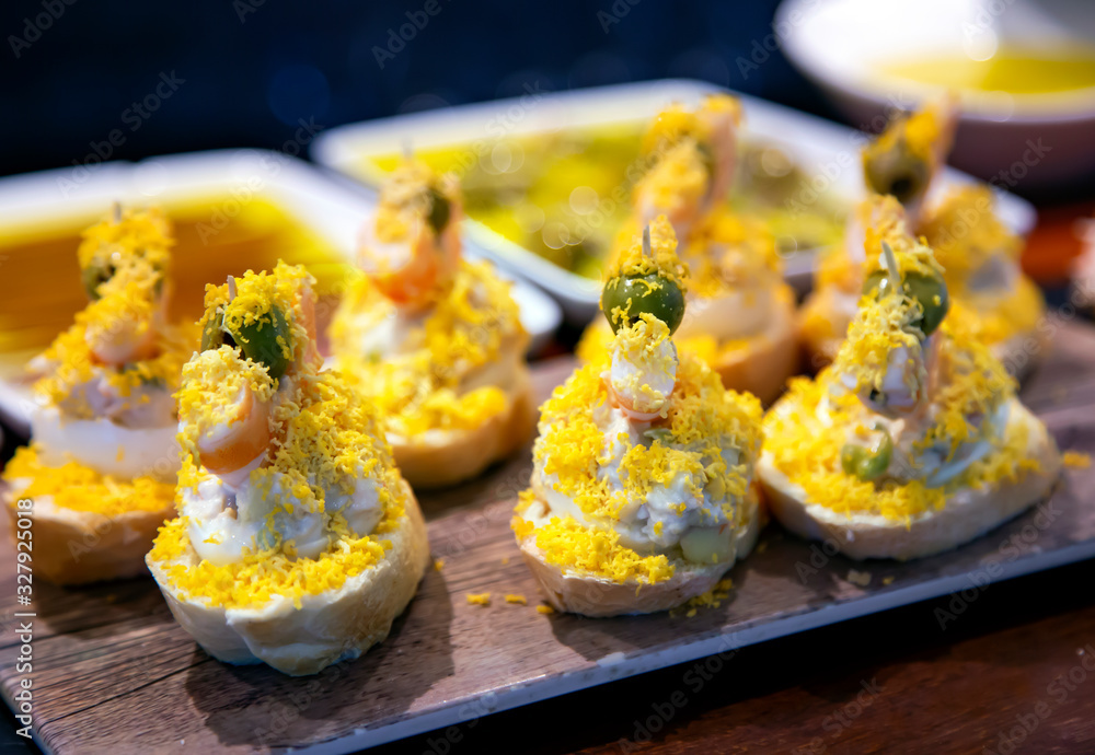 Naklejka premium Appetizing spanish tapas with salad and grated egg yolk on a wooden tray in San Sebastian, Donostia, Spain