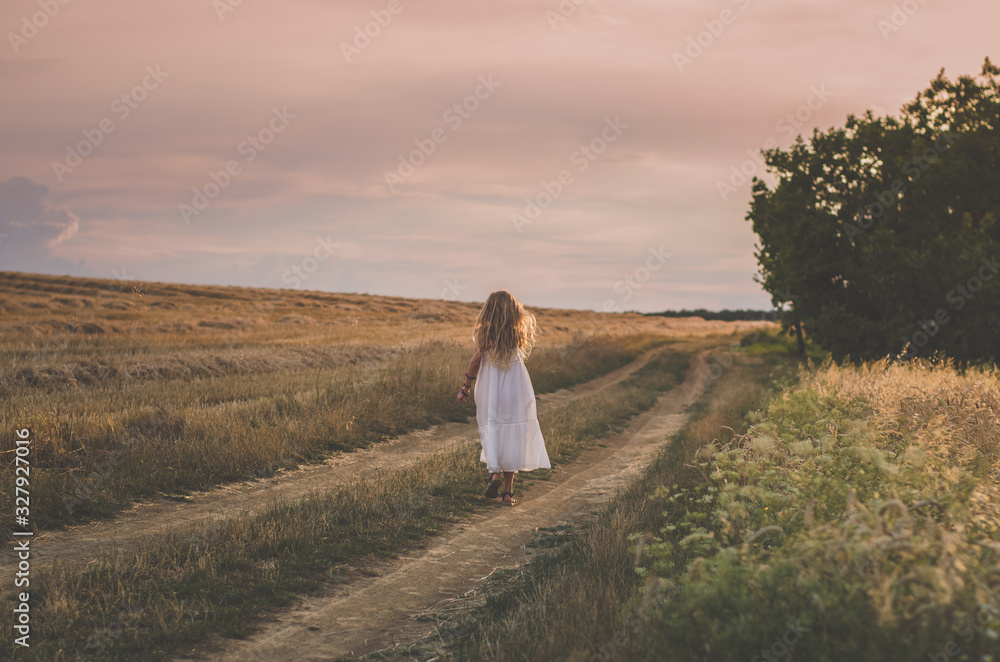 little child walking in green grass in beautiful scenic countryside