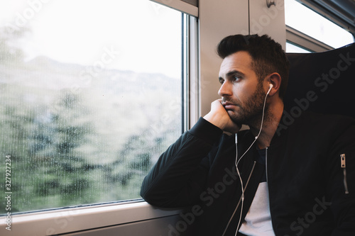 Young man traveling by train wearing earphones