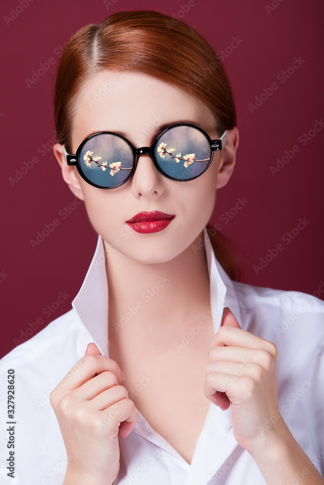 Redhead in sunglasses on red background