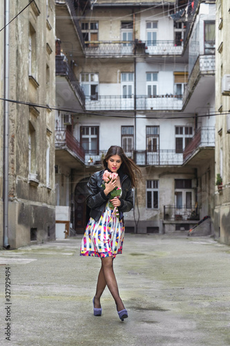 Beautiful urban woman with flowers walking down the street