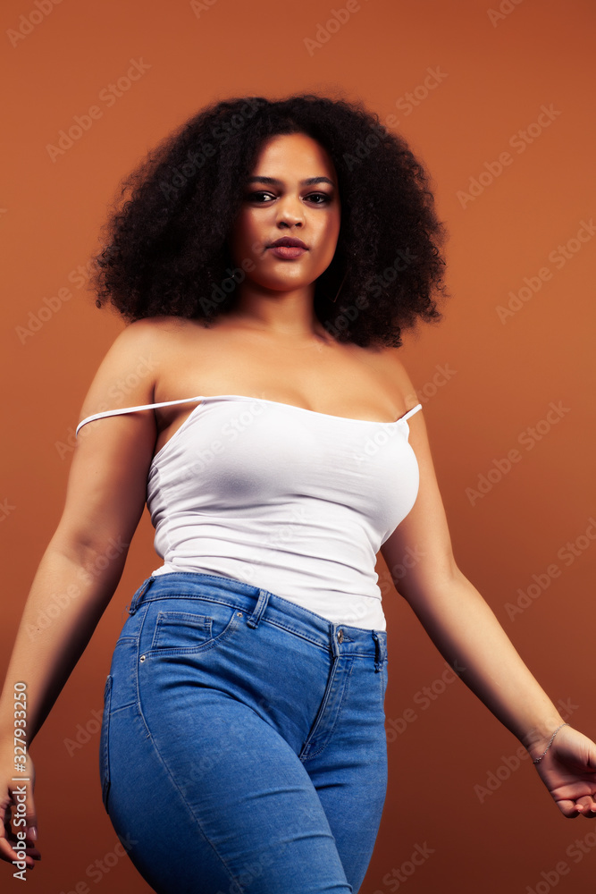 pretty young african american woman with curly hair posing cheerful gesturing on brown background, lifestyle people concept pretty young african american woman with curly hair posing cheerful gesturing on brown background, lifestyle people concept