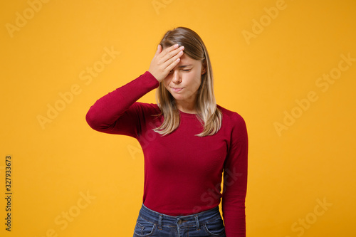 Young blonde woman in casual clothes posing isolated on yellow orange wall background studio portrait. People emotions lifestyle concept. Mock up copy space. Keeping eyes closed, put hand on forehead.