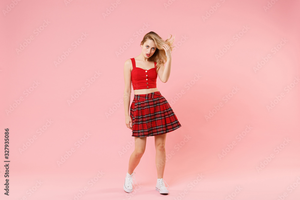 Attractive young blonde woman girl in red sexy clothes isolated on pastel pink wall background studio portrait. People sincere emotions lifestyle concept. Mock up copy space. Posing with flowing hair. Attractive young blonde woman girl in red sexy clothes isolated on pastel pink wall background studio portrait. People sincere emotions lifestyle concept. Mock up copy space. Posing with flowing hair.