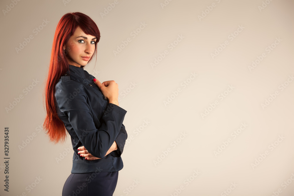 Side view of attractive young woman with long red hair resting chin on hand and looking at camera with serious expression. Beautiful girl wearing stylish business suit. Concept of beauty and style. Side view of attractive young woman with long red hair resting chin on hand and looking at camera with serious expression. Beautiful girl wearing stylish business suit. Concept of beauty and style.