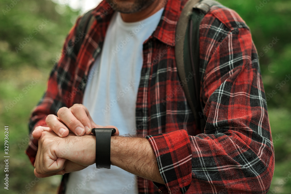 Smart watch on male hiker hand while hiking in woods