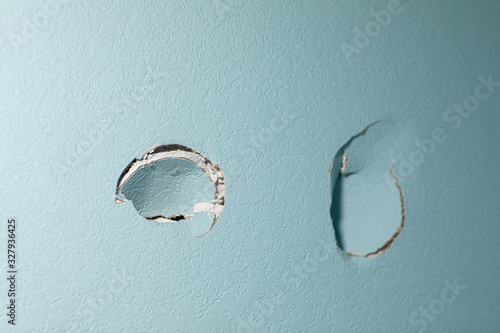 turquoise blue wall in a home with two holes in the sheetrock from a wall being punched by hand