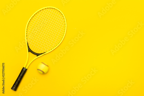 Top view of tennis rackets and ball on yellow background.