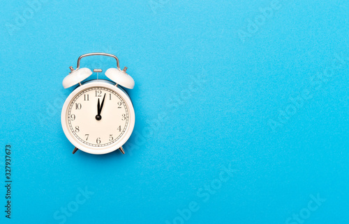 White vintage alarm clock on light blue color background