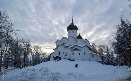Ancient orthodox christian stone temple. Pskov, Russia. The Church of St. Basil the Great on the Hill on a background of cloudy sky. Winter evening. Snowy weather. 15th century architectural monument.