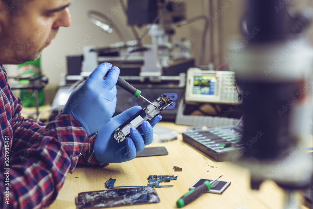 Technician repairing the smartphone's motherboard in the lab. Showing process of mobile phone repair.