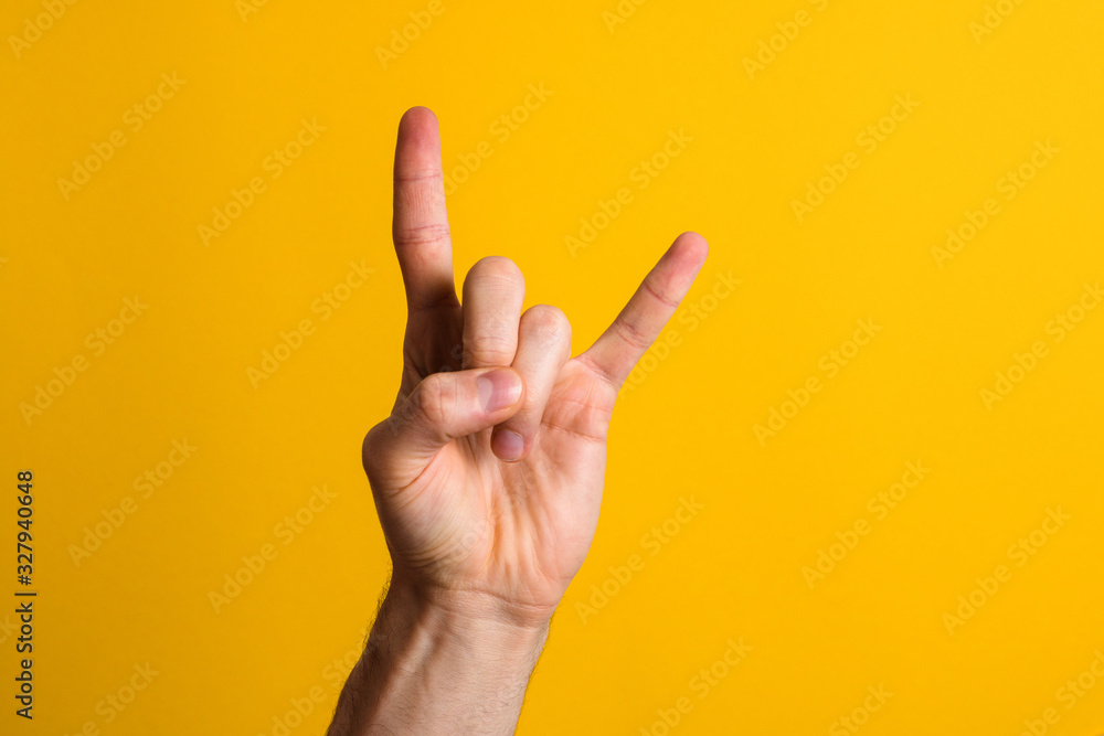 rock it. man hand showing rock sign gesture over a yellow background ...