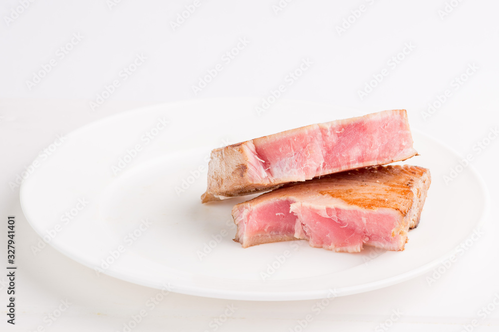 grilled tuna fish steak on a white plate with a place for garnish grilled tuna fish steak on a white plate with a place for garnish